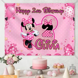May include: A pink birthday banner with Minnie Mouse, polka dots, and the text "Happy 2nd Birthday Olivia." The banner is decorated with pink balloons, bows, and stars. A cake, cupcakes, and party favors are on the table.
