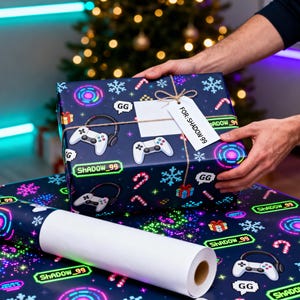 Peut inclure: Une boîte cadeau rectangulaire et un rouleau de papier cadeau avec un fond bleu foncé et un motif répétitif de manettes de jeu blanches, casques, flocons, sucres d'orge, cadeaux et le texte "ShADOW_99" et "GG" en couleurs néon.