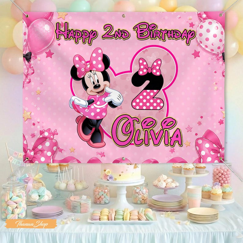 May include: A pink banner with Minnie Mouse, polka dots, and the text "Happy 2nd Birthday Olivia." The banner is part of a party scene with balloons, a cake, and various desserts. The overall theme is a children's birthday party.