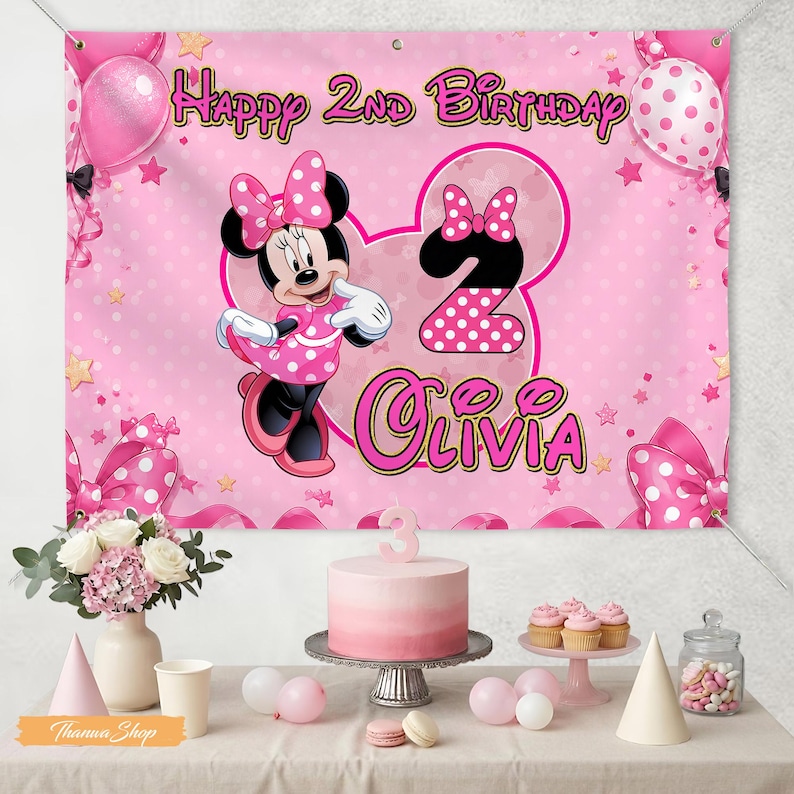 May include: A pink birthday banner with Minnie Mouse, polka dots, and the text "Happy 2nd Birthday Olivia." The banner is decorated with pink balloons, bows, and stars. A cake, cupcakes, and party favors are on the table.