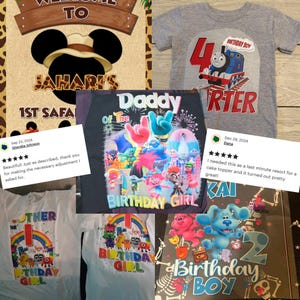May include: A collection of children's birthday-themed items. Includes a gray t-shirt with a Thomas the Tank Engine graphic, a black shirt with a colorful Trolls design, and a Blue's Clues cake topper. Also features a safari-themed sign.
