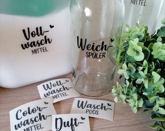May include: A set of six white labels with black text and hearts. The labels are for laundry detergent, fabric softener, and laundry pods. The labels read "Voll-wasch MITTEL", "Weich-SPÜLER", "Wou-wasch MITTEL", "Color-wasch MITTEL", "Wasch PODS", and "Duft-PERLEN".