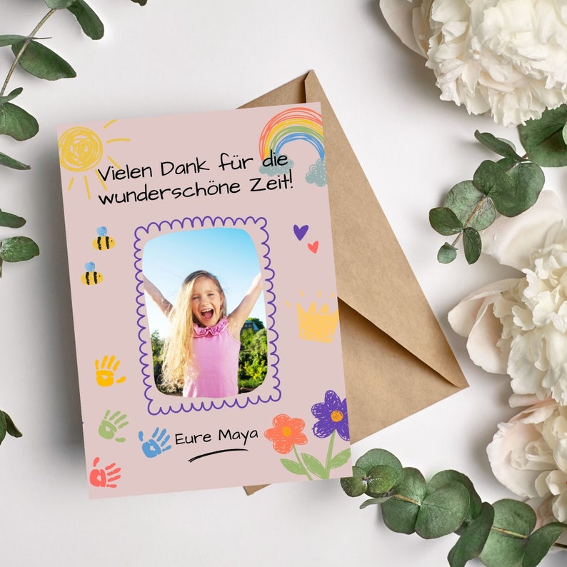 May include: A pink card with a photo of a girl smiling with her arms raised. The card has a rainbow, sun, bees, hearts, and handprints drawn on it. The text on the card reads "Vielen Dank f&uuml;r die wundersch&ouml;ne Zeit!" and "Eure Maya".