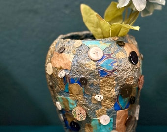 Small papier-mâché vase with decorated paper applications and buttons.