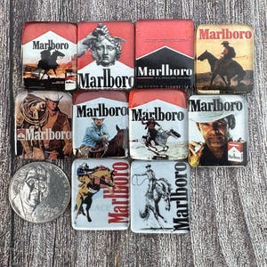 Op de afbeelding: Een verzameling rechthoekige en vierkante items met Marlboro-thema. De items tonen het Marlboro-logo en verschillende afbeeldingen, waaronder cowboys op paarden, een standbeeld en een portret. De kleurstelling is voornamelijk rood, wit en zwart.
