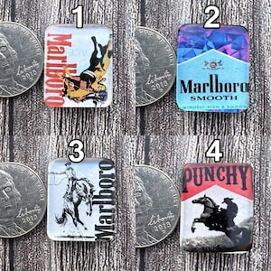 Può includere: Quattro cabochon rettangolari con immagini e testo. Uno presenta un cowboy a cavallo con il testo "Marlboro". Un altro ha un design blu e viola con "Marlboro Smooth". Il terzo ha un cowboy a cavallo con il testo "Marlboro". L'ultimo ha un cowboy a cavallo con il testo "PUNCHY".