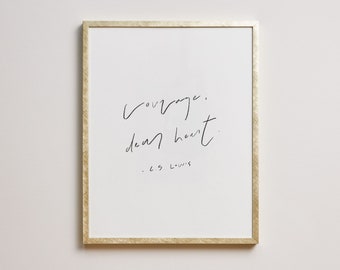 May include: A framed print with the quote "Courage, dear heart" in elegant black script on a white background. The frame has a gold finish. The author's name, C.S. Lewis, is written below the quote.