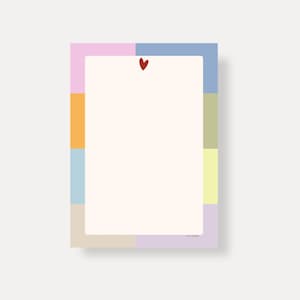 Könnte beinhalten: Ein rechteckiger Notizblock mit farbenfrohem Rand. Der Rand besteht aus Pastellblöcken in Rosa, Orange, Blau, Grün, Gelb und Lila. Oben befindet sich ein kleines rotes Herz. Der Notizblock hat ein cremefarbenes Innenteil.