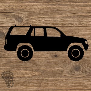 May include: A black silhouette of a sport utility vehicle featuring large off-road tires and a roof rack, shown in a side profile view. A small, faint footprint icon is positioned in the lower left corner of the graphic design.