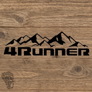 May include: Black mountain range graphic with the text "4Runner" in a bold, sans-serif font. The design is set against a wood grain background, creating a rustic aesthetic. A small footprint logo is in the lower left corner.