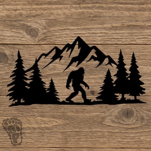 May include: Black silhouette of Bigfoot walking in front of a mountain range and pine trees. The design is set against a wood grain background. A Bigfoot footprint logo is in the lower left corner.