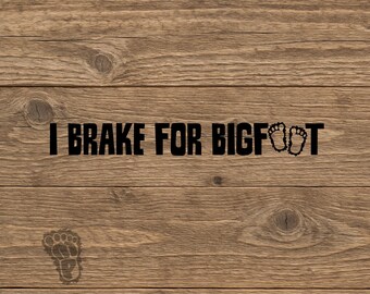 May include: A black vinyl decal featuring the text I BRAKE FOR BIGFOOT in a bold, blocky font. The letter O in BIGFOOT is replaced by a small footprint icon, and a larger, detailed footprint graphic is positioned below the main text line.