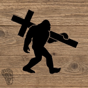 May include: Black silhouette of a Bigfoot carrying a cross. The image is set against a wood grain background. A Bigfoot footprint is in the lower left corner. The cross is held over the shoulder of the Bigfoot.
