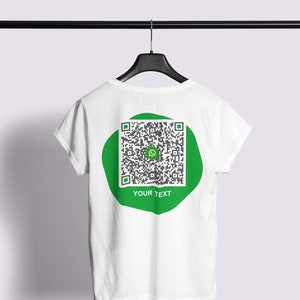 Op de afbeelding: Wit T-shirt met een groene cirkel met een zwart-witte QR-code en de tekst "YOUR TEXT" op de achterkant.