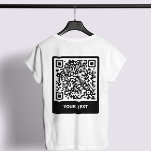 Op de afbeelding: Wit T-shirt met een zwarte QR-code en de tekst "YOUR TEXT" gedrukt op de achterkant.