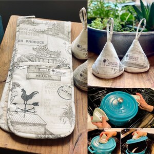 May include: A set of three white cotton pot holders with a black and white farm-themed print. The pot holders are shaped like cones and have a loop at the top for hanging. The print features a rooster, a milk carton, and the words "Fresh Milk" and "Farm Dairy Local".