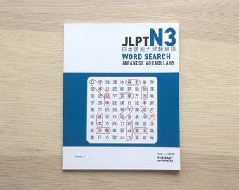 Könnte beinhalten: Ein blaues und weißes Buch mit dem Titel "JLPTN3 Japanischer Sprachtest Wortschatz-Wortsuche" mit einem japanischen Wortsuchrätsel auf dem Cover. Das Buch ist Band 1 und wird von The East Interpreter herausgegeben.