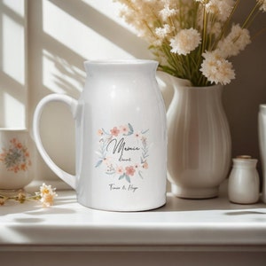 May include: White ceramic pitcher with a floral design and the text "Mamie's Donuts Timo & Hugo".