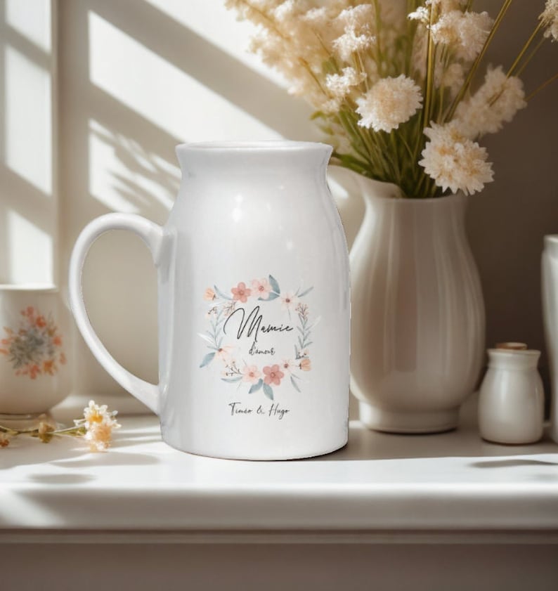 May include: White ceramic pitcher with a floral design and the text "Mamie's Donuts Timo & Hugo".
