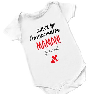 May include: White baby onesie with black text that reads "Joyeux Anniversaire Maman! Je t'aime!" with a red heart and three smaller red hearts.