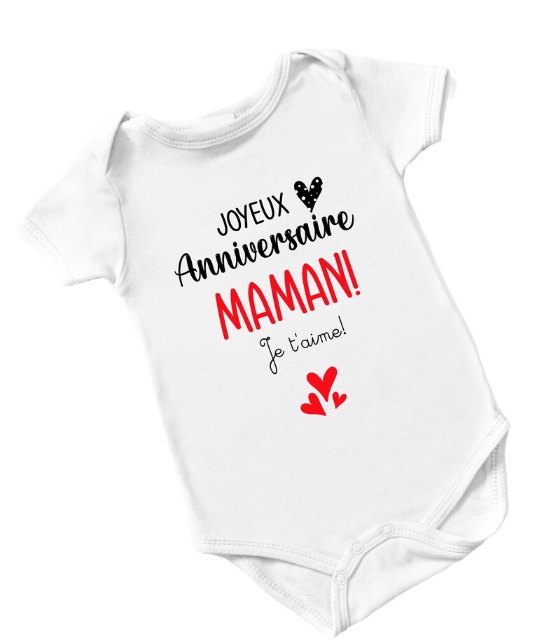 May include: White baby onesie with black text that reads "Joyeux Anniversaire Maman! Je t'aime!" with a red heart and three smaller red hearts.