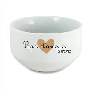 Peut inclure: Bol en céramique blanc avec l'inscription "Papa d'amour" et un cœur marron. Le texte "DE GASPARD" est également imprimé sur le bol. Le bol a une forme arrondie et une finition lisse et brillante.