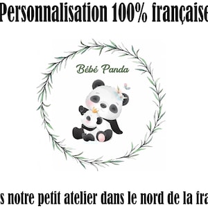 May include: A black and white panda bear illustration with a baby panda bear. The illustration is surrounded by a green leafy wreath. The text "B&eacute;b&eacute; Panda" is written above the panda bears.