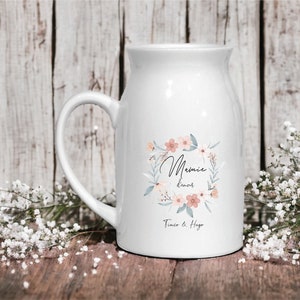 May include: White ceramic mug with a floral wreath design and the text "Mamie d'amour Tim&eacute;o & Hugo".