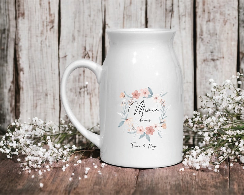 May include: White ceramic mug with a floral wreath design and the text "Mamie d'amour Tim&eacute;o & Hugo".