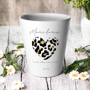 Peut inclure: Pot de fleurs en céramique blanche avec un cœur imprimé léopard noir et or. Le pot porte les inscriptions "Mamie d'amour" et "Tu es la meilleure mamie du monde".