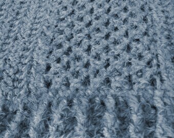 May include: Close-up of a blue knitted fabric with a textured, fuzzy surface.