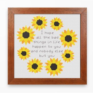 May include: Cross-stitch pattern featuring a circle of yellow sunflowers with black centers and the text "I hope all the bad things in life happen to you and nobody else but you".
