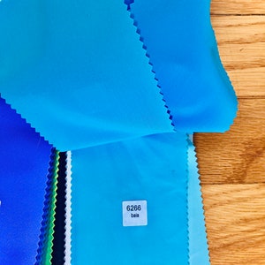 May include: A stack of fabric swatches in various shades of blue, with a white label that reads "6266 bala".