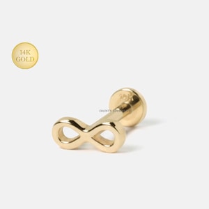 May include: A single gold-colored infinity symbol earring. The earring is made of 14K gold and has a flat, round backing. The infinity symbol is a continuous loop design. The earring is from Dainty Studio NYC.
