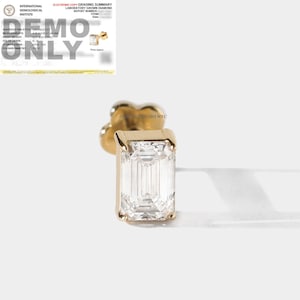 May include: A gold earring with a single emerald-cut diamond. The diamond is clear and has a brilliant shine.