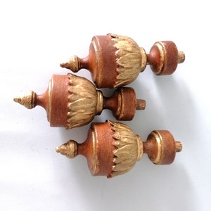 May include: Three wooden finials with gold leaf accents. The finials are brown and have a decorative design. They are perfect for adding a touch of elegance to any home decor project.
