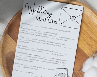 Puede incluir: Un juego de palabras imprimibles para bodas, "Wedding Mad Libs", con una ilustración de un sobre en blanco y negro. El texto dice "Wedding Mad Libs" e incluye instrucciones para completar los espacios en blanco con palabras para crear una historia divertida.