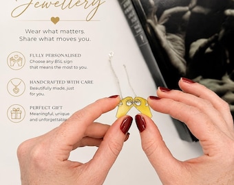 Può includere: Una collana color argento con due ciondoli gialli traslucidi a forma di mano che formano un segno BSL. I ciondoli sono uniti da una sottile catenina argentata. Il testo sull'immagine recita: PERSONALISED BSL Jewellery, Wear what matters. Share what moves you, FULLY PERSONALISED, HANDCRAFTED WITH CARE, PERFECT GIFT, YOUR SIGN. YOUR STORY. Forever with you. PERSONALISED JEWELLERY. MADE WITH LOVE. WORN WITH PRIDE.