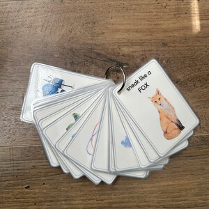 K&ouml;nnte beinhalten: Ein Satz von Karteikarten mit verschiedenen Bildern und dem Text "sneak like a FOX" auf einer Karte. Die Karten werden mit einem silbernen Ring zusammengehalten.