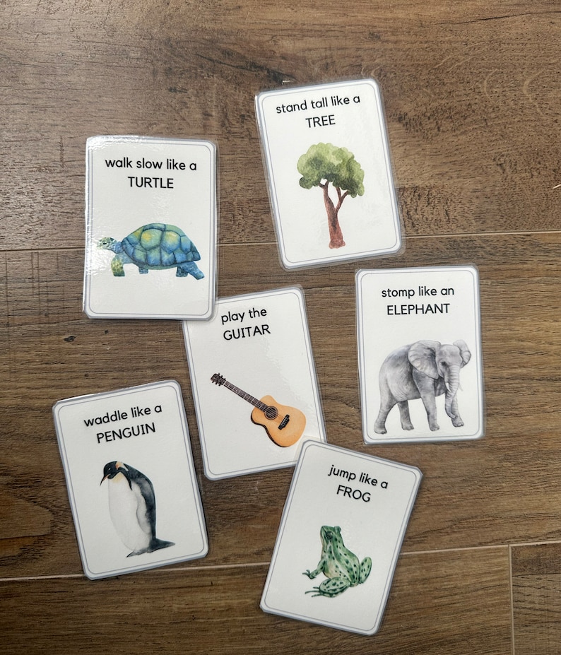 K&ouml;nnte beinhalten: Sechs illustrierte Karten mit Anweisungen f&uuml;r ein Bewegungsspiel. Die Karten zeigen eine Schildkr&ouml;te, einen Baum, eine Gitarre, einen Elefanten, einen Pinguin und einen Frosch.
