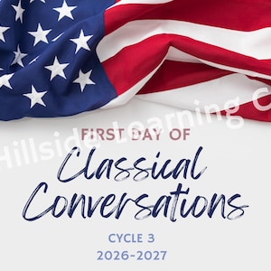 May include: A white sign featuring the text FIRST DAY OF Classical Conversations CYCLE 3 2026-2027 in dark blue and red lettering. The top of the sign is draped with a folded American flag displaying white stars on a blue field and red and white stripes.