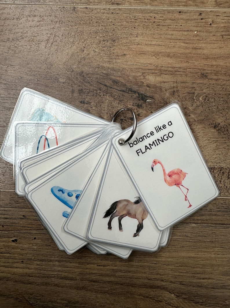 K&ouml;nnte beinhalten: Ein Satz von Karteikarten mit Bildern und Text. Die Karten werden mit einem Metallring zusammengehalten. Eine Karte zeigt einen Flamingo mit dem Text "balance like a FLAMINGO".