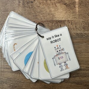 K&ouml;nnte beinhalten: Ein Satz von Karteikarten mit einer Roboterillustration auf der Vorderseite. Der Text auf der Vorderseite lautet "say it like a ROBOT".