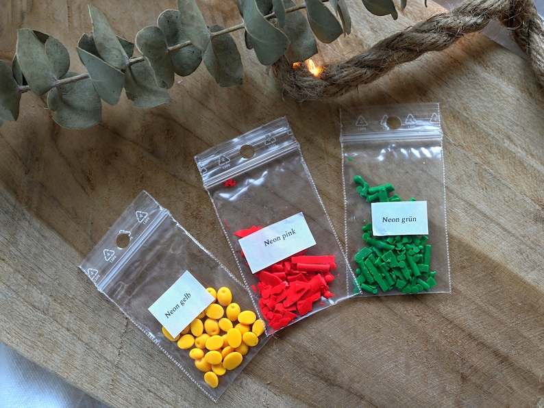 May include: Three small bags of colorful sprinkles. The bags are labeled "Neon gelb", "Neon pink", and "Neon gr&uuml;n".