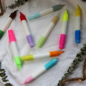 May include: Assortment of colorful candles with a white base. The candles are two-toned with a variety of colors including green, red, pink, blue, yellow, and orange.