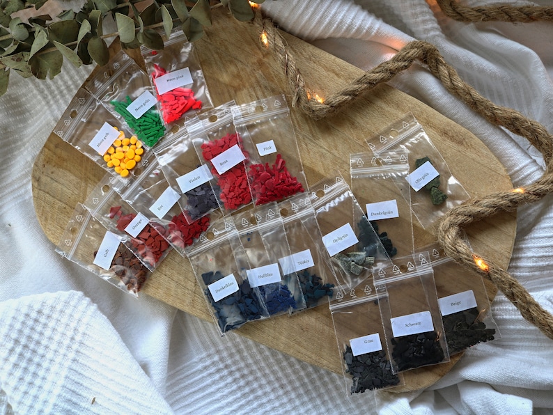 May include: Assortment of small plastic bags filled with colorful sprinkles. The bags are labeled with the color of the sprinkles inside, such as "Red", "Orange", "Yellow", "Green", "Blue", "Black", and "Brown".