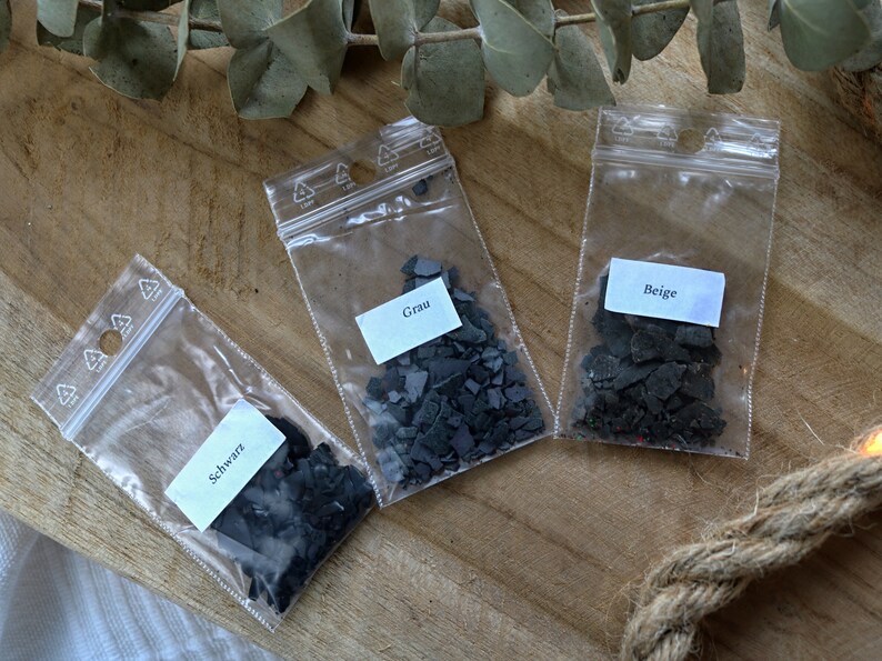 May include: Three small plastic bags containing black, gray, and beige mica powder. The bags are labeled "Schwarz", "Grau", and "Beige".