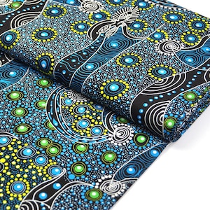 May include: Folded fabric displaying a striking abstract pattern. The design incorporates a black backdrop with swirling white lines and circular motifs in shades of blue, green, and yellow. The material is likely cotton or a similar fabric.