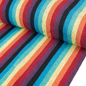 Op de afbeelding: Een rol kleurrijk gestreept stof met een regenboogpatroon. De stof is geweven met zwarte, rode, oranje, gele, groene, blauwe en paarse strepen.