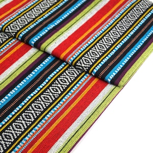Op de afbeelding: Multicolor gestreepte stof met een geometrisch patroon. De stof is dubbelgevouwen en de strepen zijn verticaal gerangschikt.